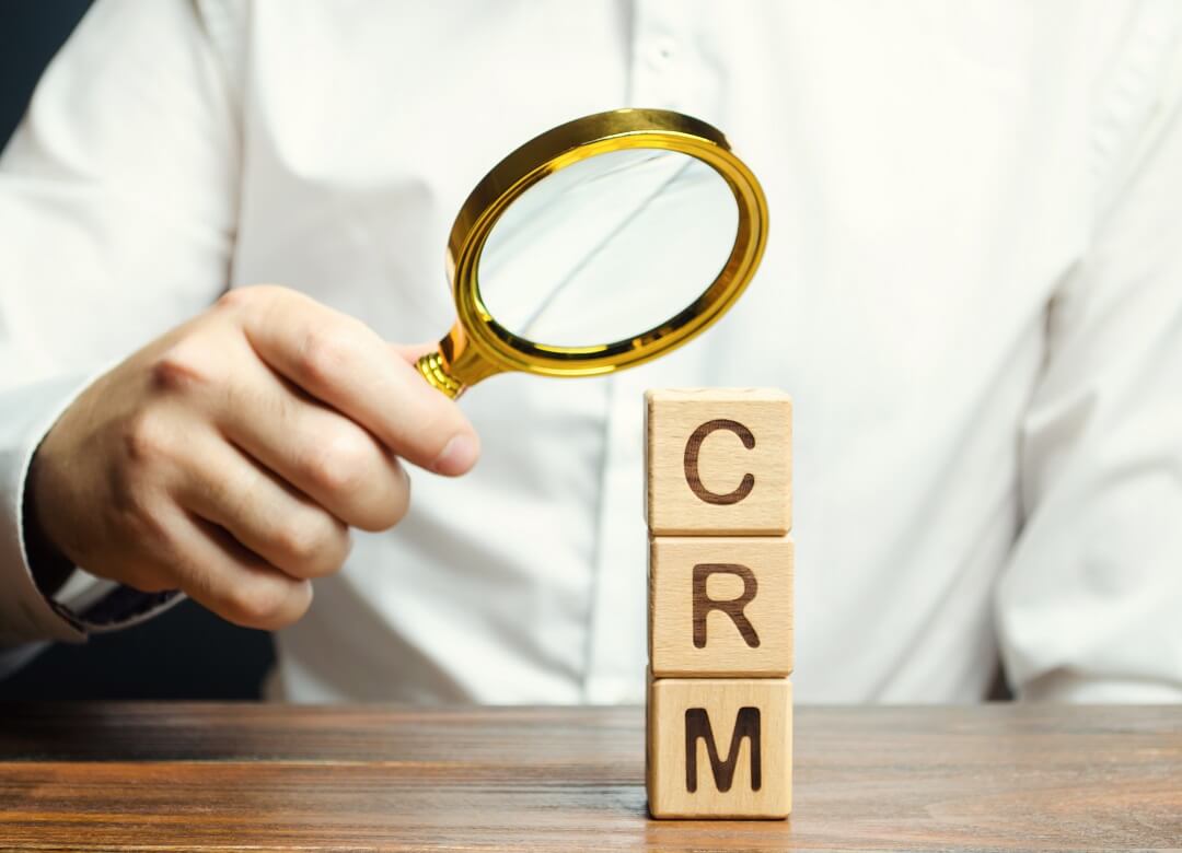 Wooden blocks with the word CRM and a man with magnifying glass